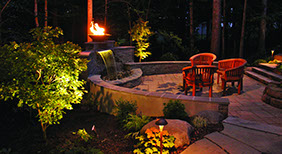 Retaining wall waterfall with fire and patio set at night. Formal Falls.
